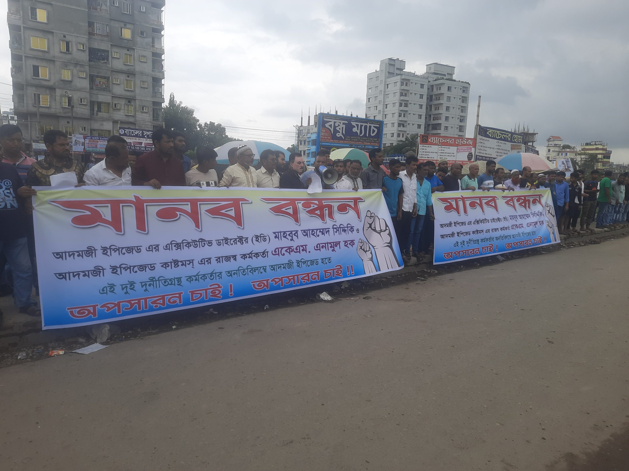 আদমজী ইপিজেডের সামনে দুর্নীতিবাজ কর্মকর্তাদের বিরুদ্ধে মানববন্ধন করছেন ভুক্তভোগী ব্যবসায়ীরা।